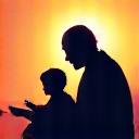 A silhouette of a grandfather reading to his grandchild.