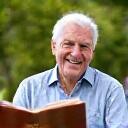 A happy gentleman reading a book outdoors.